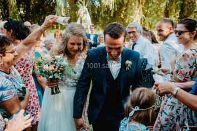 Des personnes dansent et lèvent les bras dans une ambiance festive, éclairée par des lumières colorées.