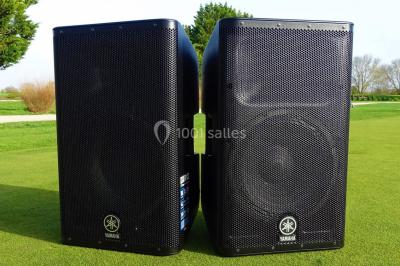 Des personnes dansent et lèvent les bras dans une ambiance festive, éclairée par des lumières colorées.