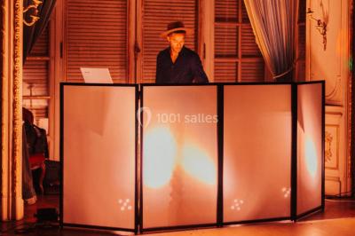 Des personnes dansent et lèvent les bras dans une ambiance festive, éclairée par des lumières colorées.