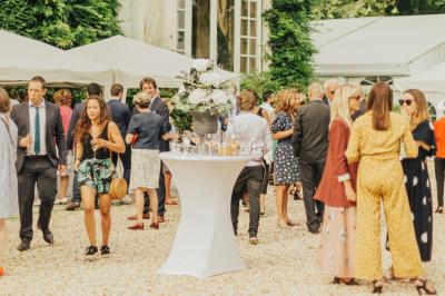 Des personnes dansent et lèvent les bras dans une ambiance festive, éclairée par des lumières colorées.