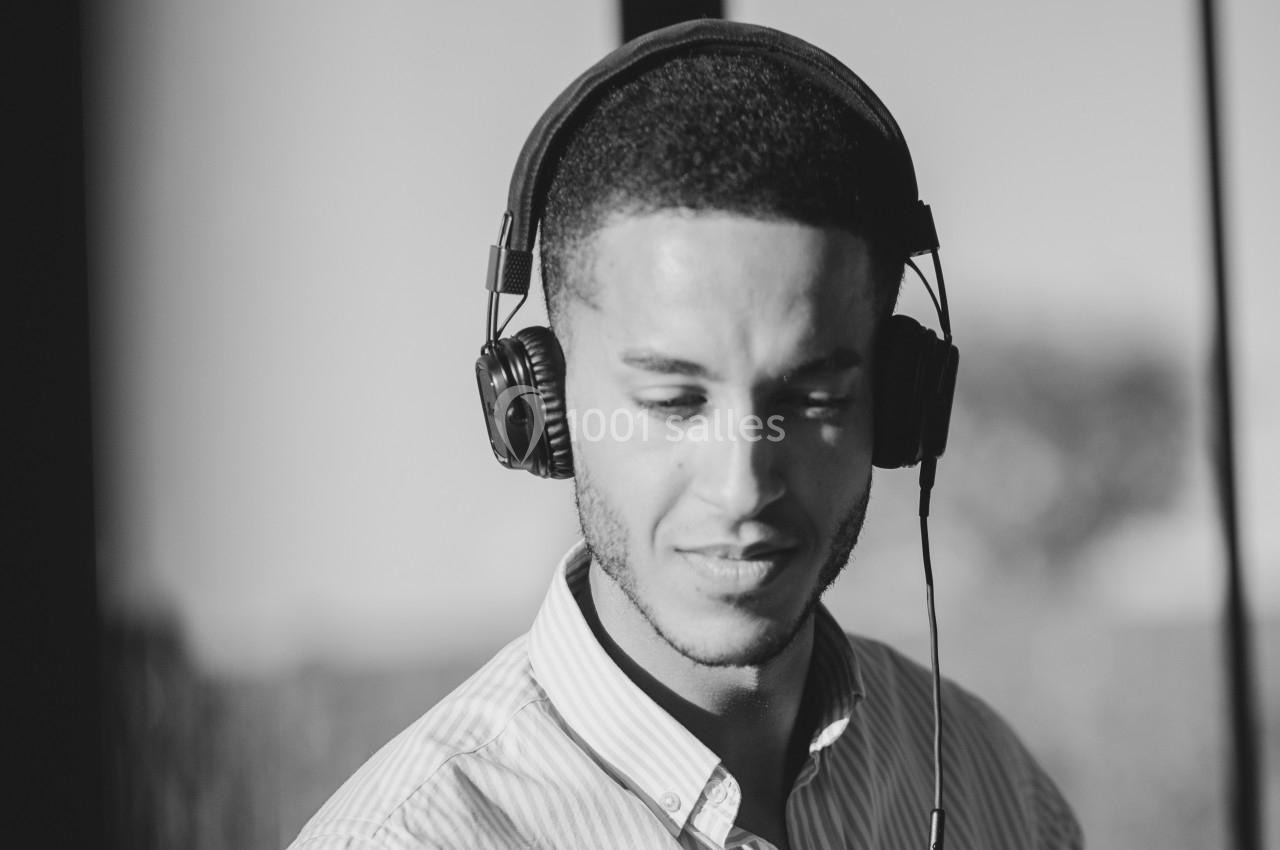 Homme portant un casque audio, regardant vers le bas dans un environnement lumineux en noir et blanc.