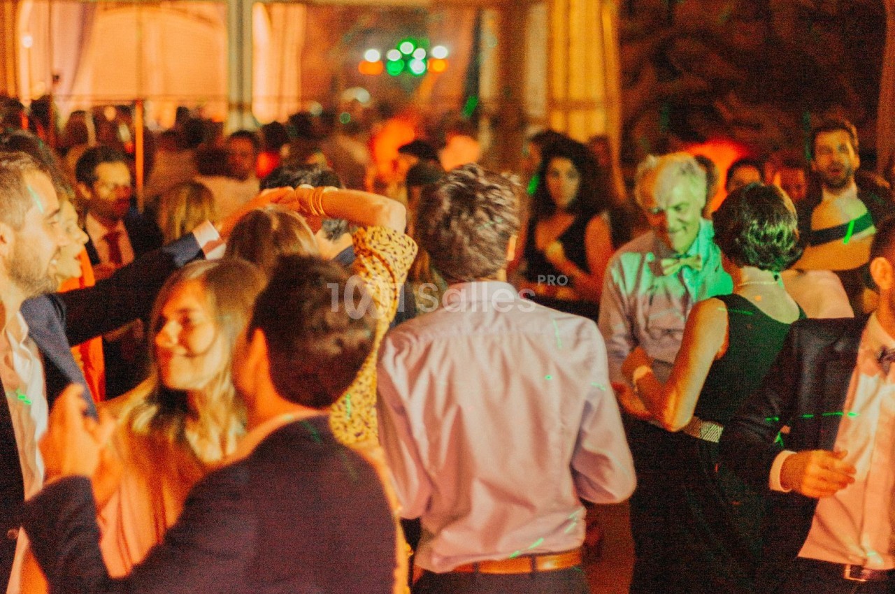Personnes dansant et discutant lors d'une soirée animée avec éclairages colorés en intérieur.