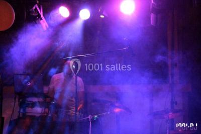 Salle décorée avec un sapin de Noël, éclairages colorés au sol et matériel de DJ installé sur une estrade.