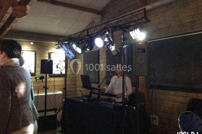 Salle décorée avec un sapin de Noël, éclairages colorés au sol et matériel de DJ installé sur une estrade.