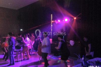 Salle décorée avec un sapin de Noël, éclairages colorés au sol et matériel de DJ installé sur une estrade.