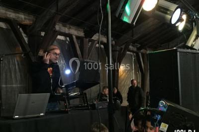 Salle décorée avec un sapin de Noël, éclairages colorés au sol et matériel de DJ installé sur une estrade.