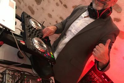 Salle décorée avec un sapin de Noël, éclairages colorés au sol et matériel de DJ installé sur une estrade.