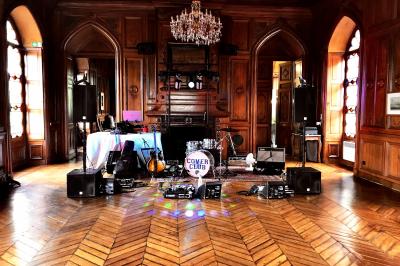 Salle décorée avec un sapin de Noël, éclairages colorés au sol et matériel de DJ installé sur une estrade.