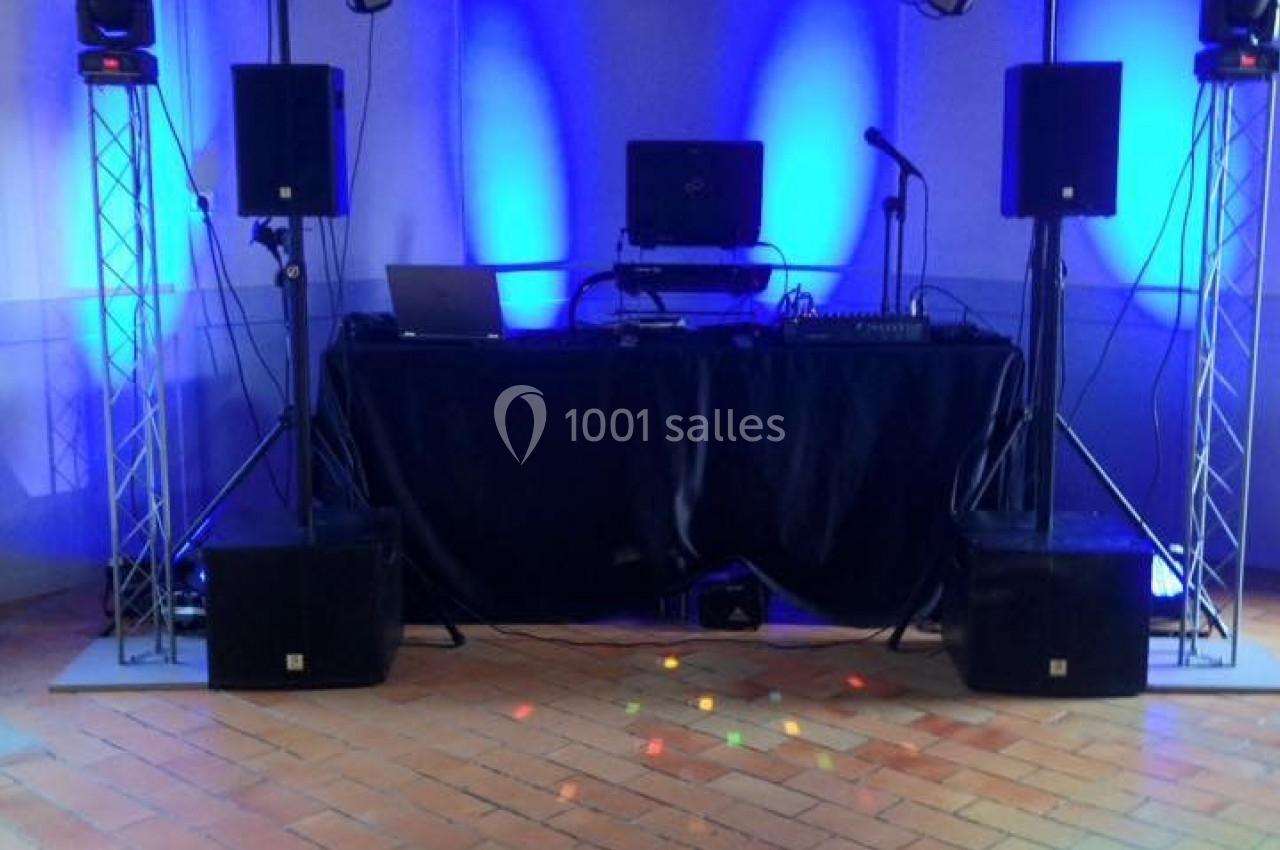 Installation de matériel de sonorisation et éclairage avec une table de mixage dans une salle aux murs éclairés en bleu.