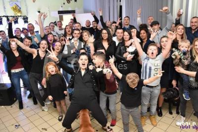 Un homme et une femme sourient devant un fond décoré de feuillage et de rideaux blancs.