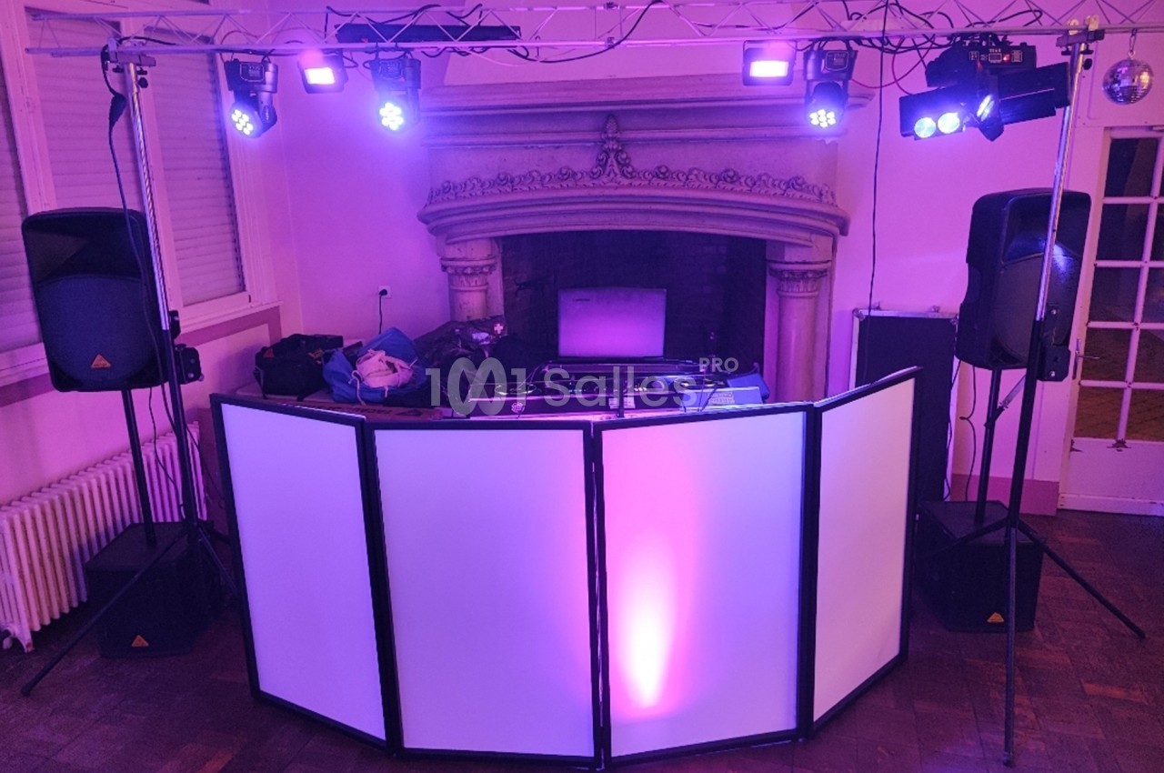 Installation de matériel de sonorisation et éclairage avec une table de mixage devant une cheminée dans une salle.