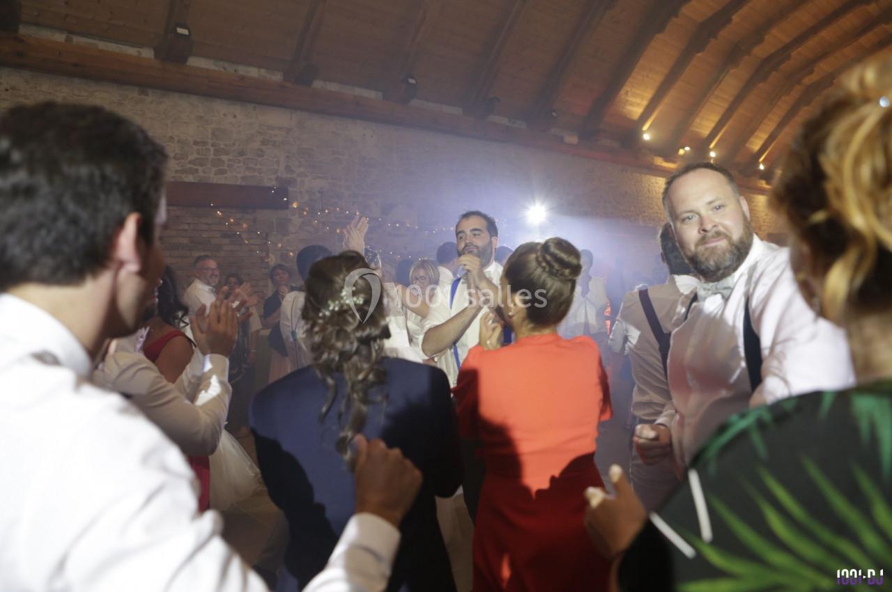 Un groupe de personnes dansant et s'amusant lors d'une fête dans une salle aux murs en pierre et au plafond en bois.
