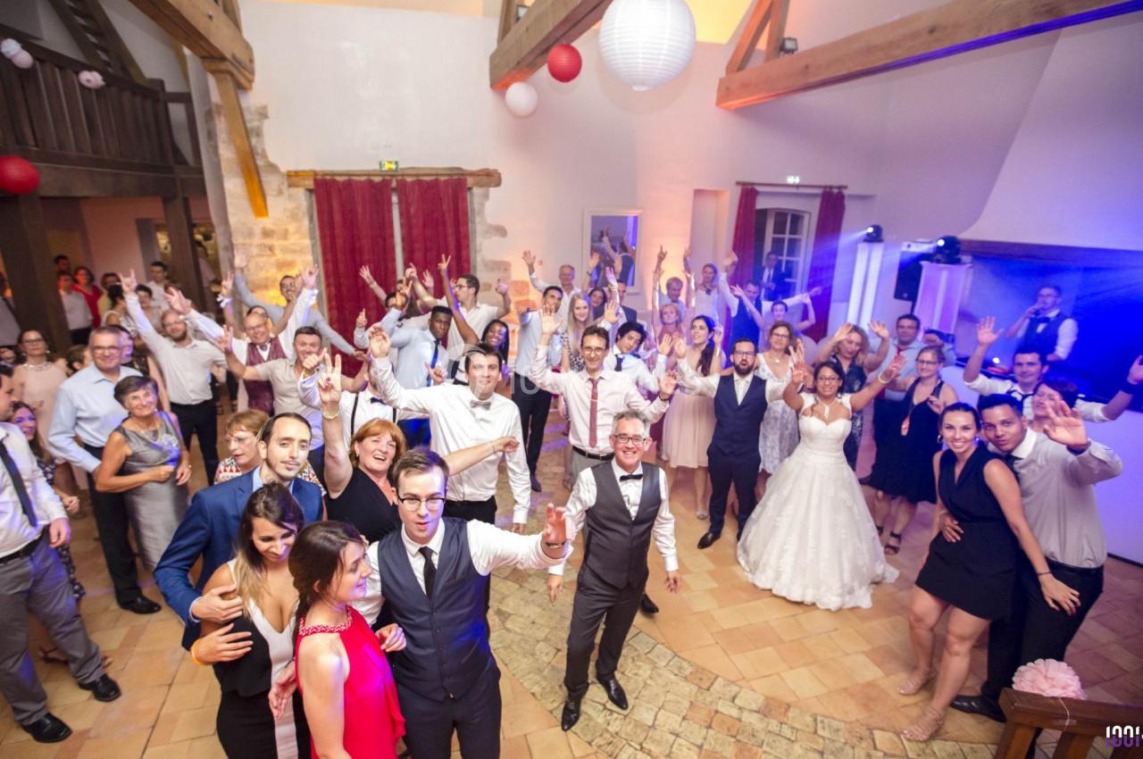 Groupe de personnes dans une salle festive, certaines dansent et sourient, ambiance conviviale et éclairage chaleureux.