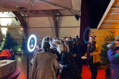 Groupe de musiciens jouant sur une scène couverte en plein air, éclairée par des lumières colorées, avec un public devant.