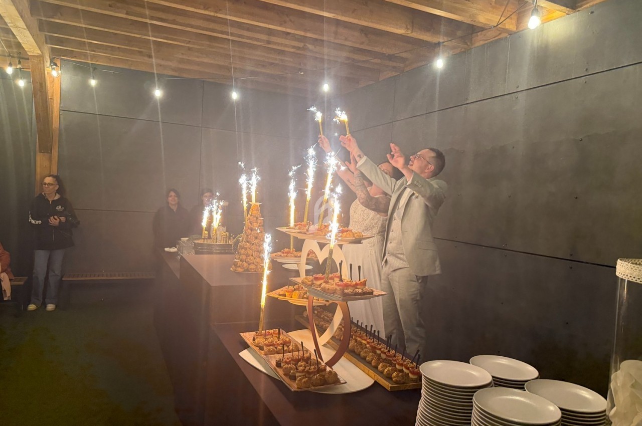 Des personnes célèbrent avec des coupes et des fontaines lumineuses autour d'un buffet dans une salle éclairée.