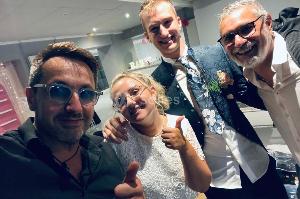 Quatre personnes souriantes posent ensemble dans un intérieur lumineux, deux d'entre elles font un signe de pouce levé.