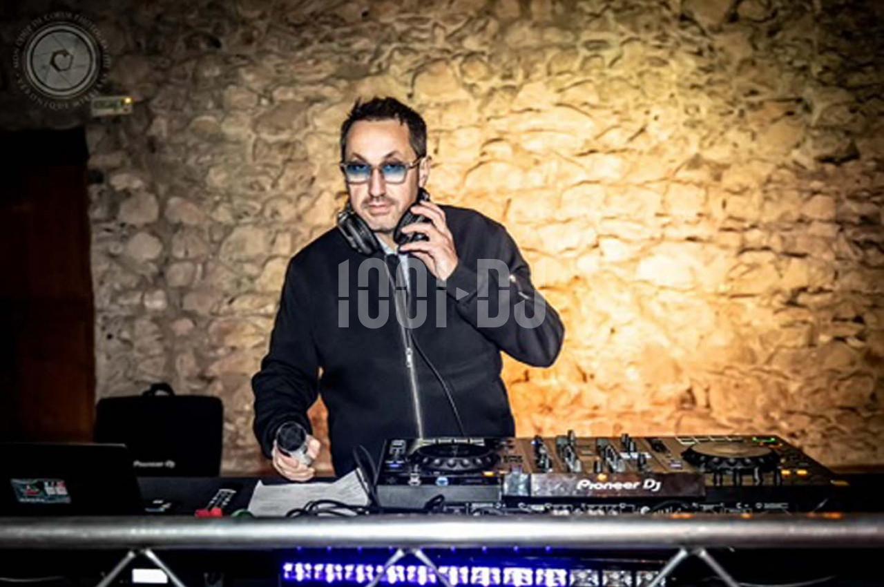 Un DJ mixant de la musique sur une table de mixage dans une salle avec un mur en pierre en arrière-plan.