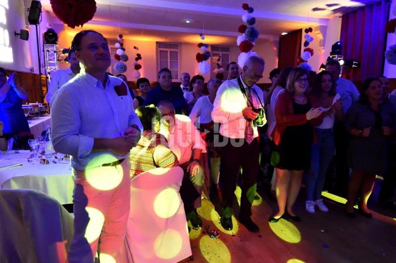 Groupe de personnes debout et assises dans une salle éclairée par des lumières colorées lors d'un événement festif.