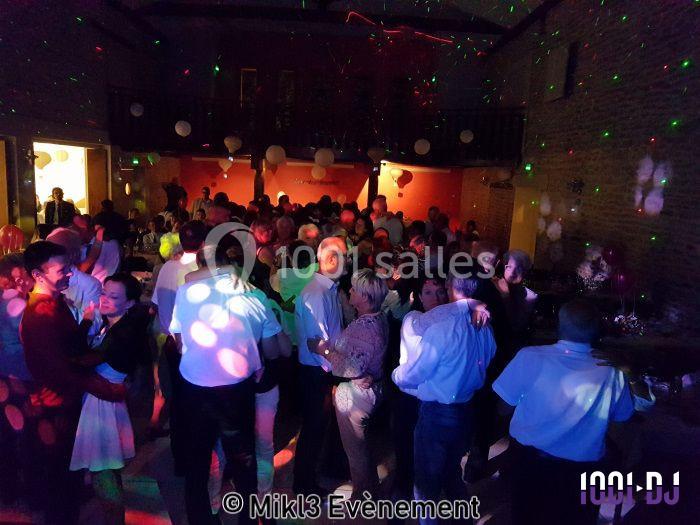 Groupe de personnes dans une salle éclairée par des lumières colorées, dansant et discutant lors d'un événement festif.