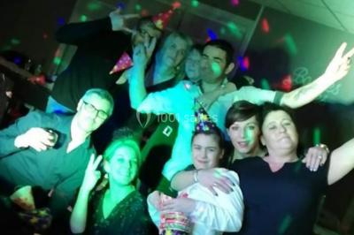 Deux mains entrelacées sur une table, avec des verres et une ambiance romantique en arrière-plan.