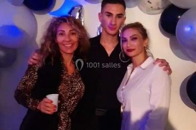 Deux mains entrelacées sur une table, avec des verres et une ambiance romantique en arrière-plan.