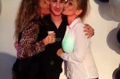 Deux mains entrelacées sur une table, avec des verres et une ambiance romantique en arrière-plan.