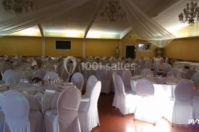 Deux mains entrelacées sur une table, avec des verres et une ambiance romantique en arrière-plan.