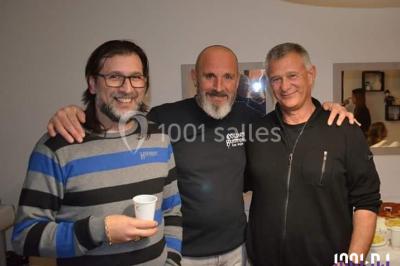 Deux mains entrelacées sur une table, avec des verres et une ambiance romantique en arrière-plan.