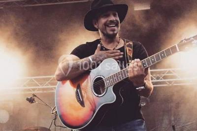 Deux mains entrelacées sur une table, avec des verres et une ambiance romantique en arrière-plan.