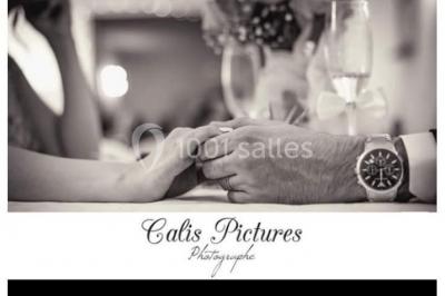 Deux mains entrelacées sur une table, avec des verres et une ambiance romantique en arrière-plan.