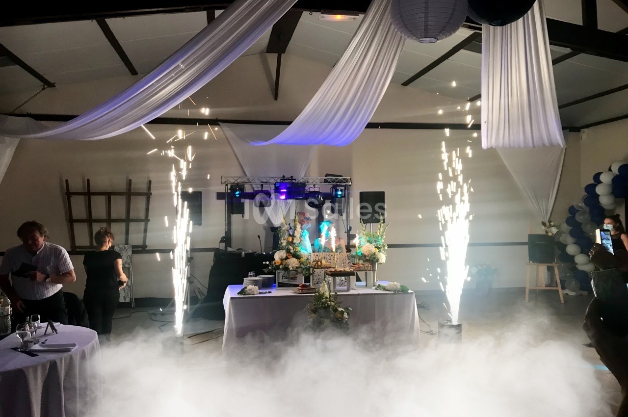 Effets pyrotechniques et décorations lumineuses autour d'une table ornée de fleurs dans une salle de réception.