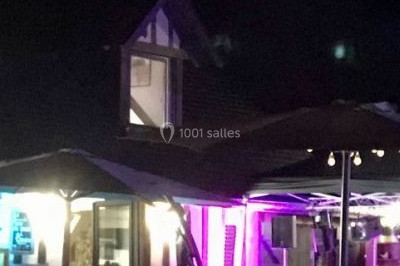 Salle de réception décorée avec des voilages blancs, des tables dressées et des chaises couvertes de housses.