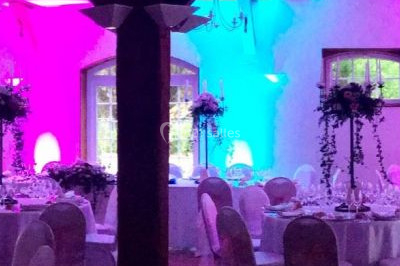 Salle de réception décorée avec des voilages blancs, des tables dressées et des chaises couvertes de housses.