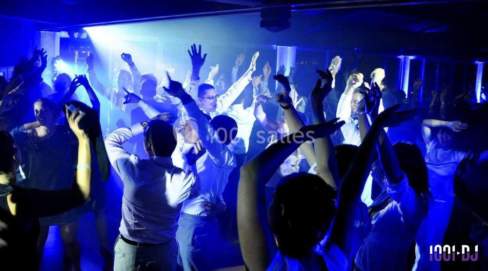 Personnes dansant sous des lumières bleues dans une ambiance festive en intérieur.
