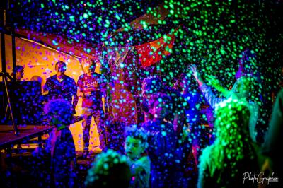 Miniature DJ Belhade (Landes) - Caribbean Sounds #9 Groupe de personnes réunies en soirée en plein air, éclairées par des guirlandes lumineuses et des lampadaires.