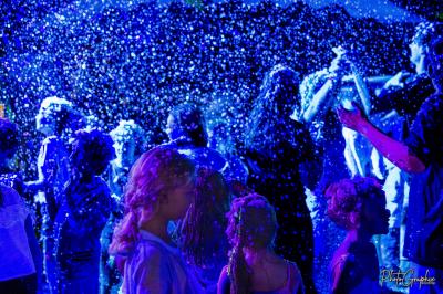 Miniature DJ Belhade (Landes) - Caribbean Sounds #11 Groupe de personnes réunies en soirée en plein air, éclairées par des guirlandes lumineuses et des lampadaires.