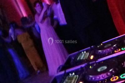 Des personnes dansent sous des lumières rouges dans une salle ornée de décorations murales et de lustres.