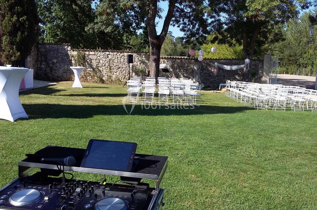 Installation d'une table de mixage en extérieur avec des chaises blanches disposées pour un événement dans un jardin.