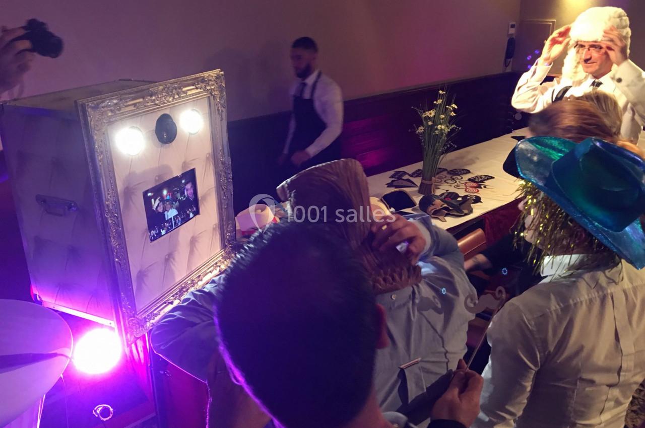 Des personnes utilisent un photobooth lors d'un événement, essayant des accessoires devant un écran lumineux.