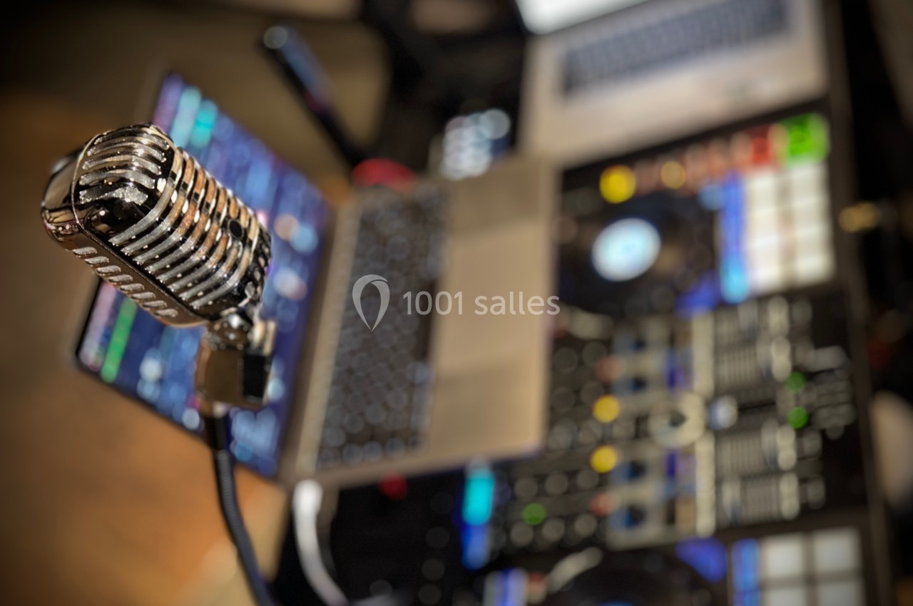 Micro vintage en gros plan devant un équipement de mixage et un ordinateur portable flou en arrière-plan.