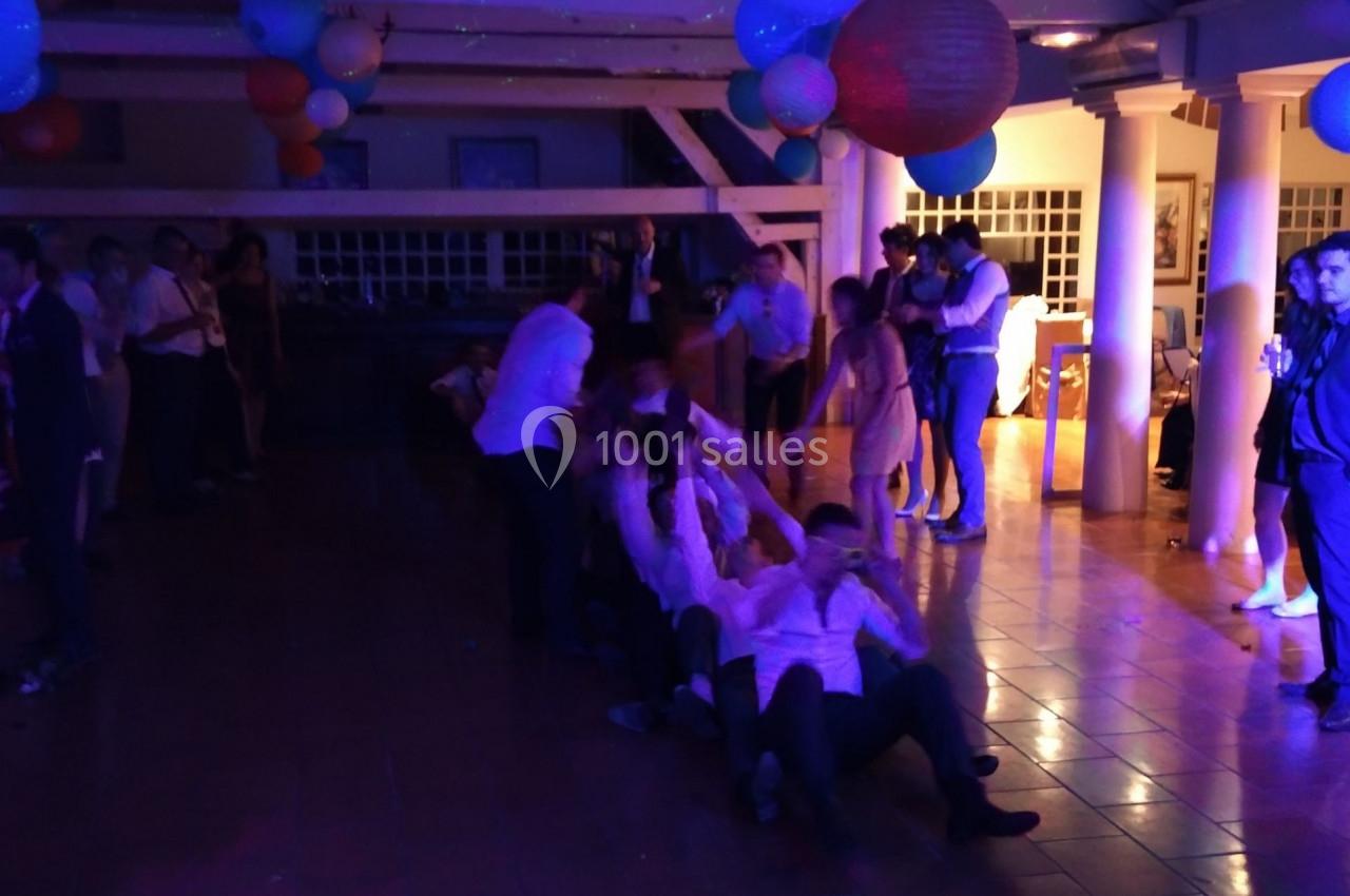 Des personnes participent à un jeu collectif dans une salle décorée, éclairée par des lumières colorées.