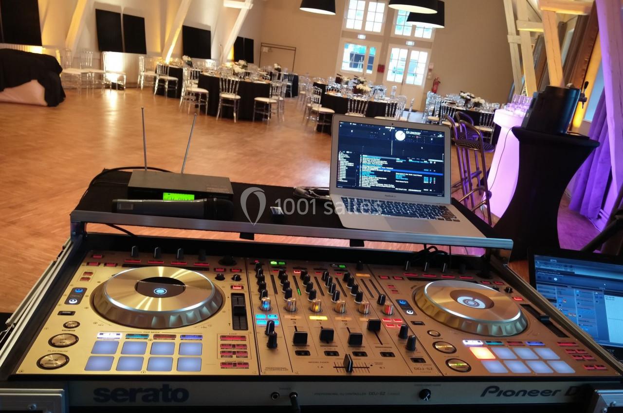 Table de mixage DJ avec ordinateur portable dans une salle de réception préparée pour un événement.