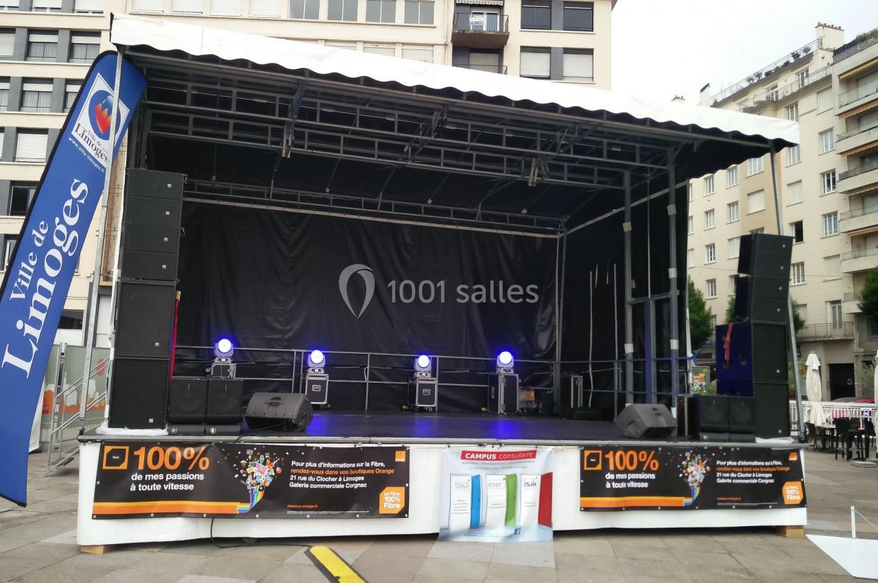 Scène extérieure avec éclairages violets, bannière ’Ville de Limoges’ et publicités en bas de l'estrade.