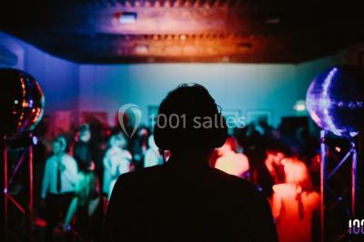 Un couple danse sur une piste éclairée par des lumières colorées, entouré de spectateurs dans une salle festive.