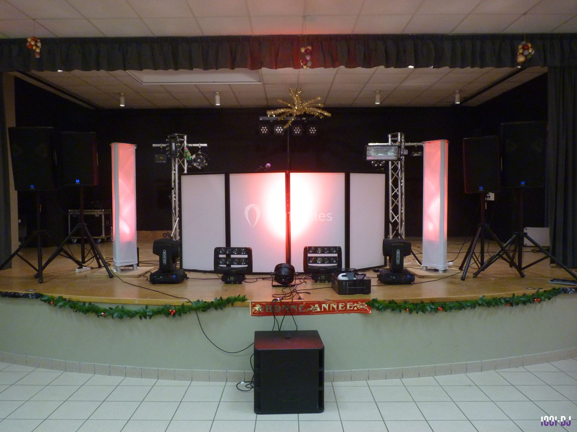 Configuration d'une scène avec éclairages colorés, haut-parleurs et équipements audio-visuels dans une salle de spectacle.