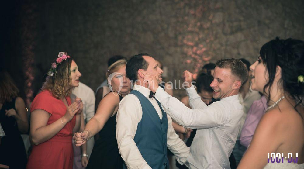 Des invités dansent et s'amusent lors d'une fête dans une salle aux murs en pierre.