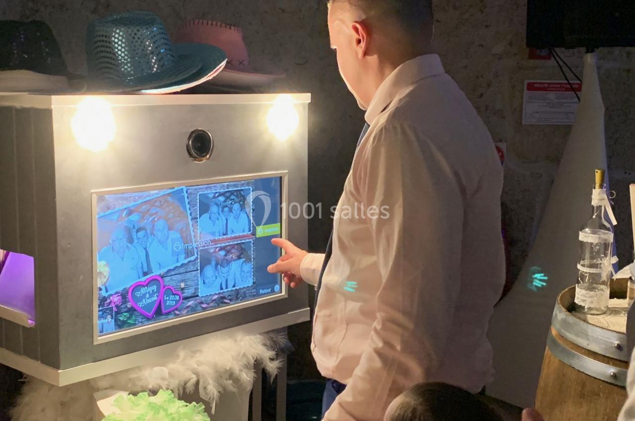 Un homme utilise une borne photo interactive lors d'un événement, entouré d'accessoires festifs.