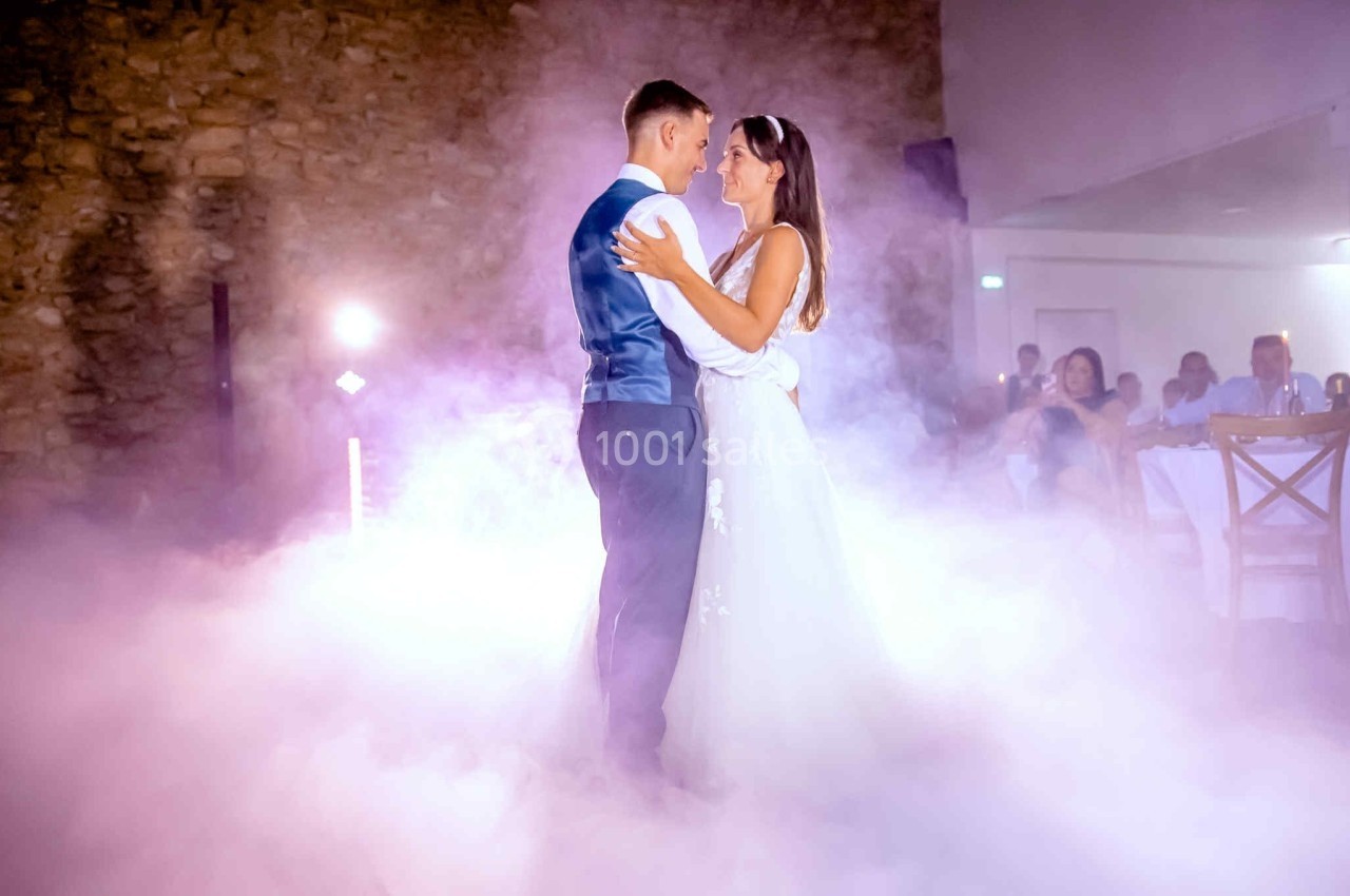 Un couple danse dans une ambiance romantique avec des effets de fumée et un éclairage tamisé.