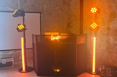 Salle décorée pour un événement avec éclairage violet, machines à fumée et équipements audio devant une baie vitrée.