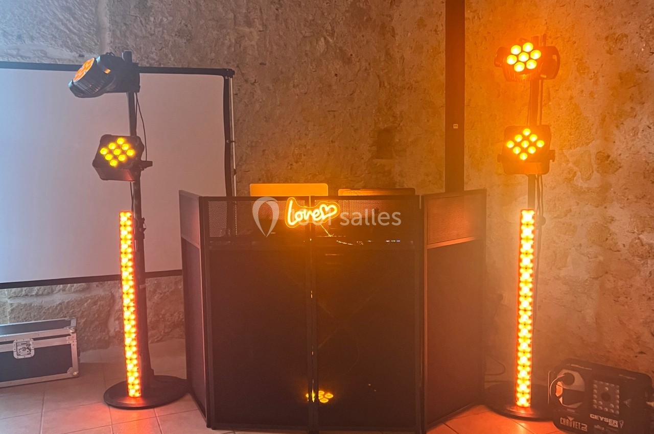 Installation de matériel de sonorisation et éclairage avec projecteurs orange et panneau lumineux ’love’.